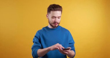  Umutla dolu genç bir adam cep telefonundaki bilgiye üzülüyor. Sarı arkaplan