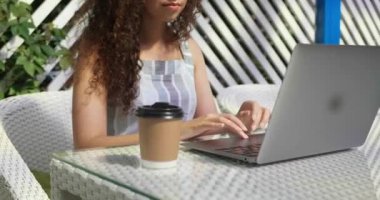 Kafede dizüstü bilgisayar kullanan genç bir kadın, yakın plan. Kamera sola hareket ediyor