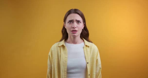 Verängstigte Junge Frau Versteckt Sich Hinter Händen Auf Gelbem Hintergrund — Stockvideo