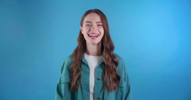 美丽的年轻女子在浅蓝色的背景上大笑 — 图库视频影像