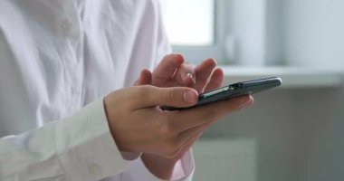 Kapalı mekanda akıllı telefondan yazı yazan bir kadın.