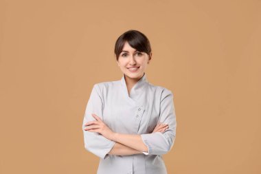 Bej arka planda tıbbi üniformalı kozmetolog.