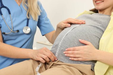 Hamilelik kontrolü. Klinikte hastanın karnını ölçen doktor, yakın plan.