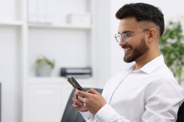 Ofiste akıllı telefon kullanan mutlu genç adam, mesaj için boşluk