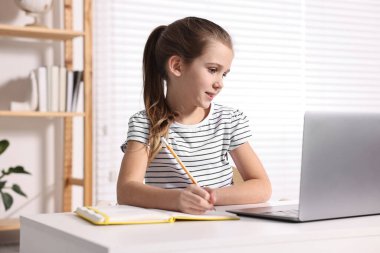 E-öğrenme. İçerideki masada online ders sırasında not alan tatlı kız.