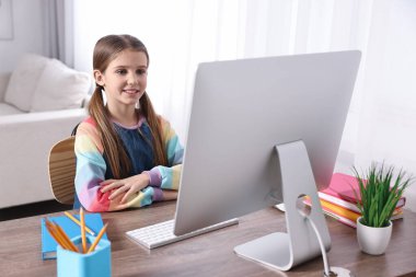 E-öğrenme. İçerideki masada çevrimiçi ders sırasında bilgisayar kullanan sevimli kız.