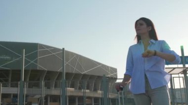 Havaalanı yakınlarında taksi beklerken bavulunu kontrol eden genç bir kadın.