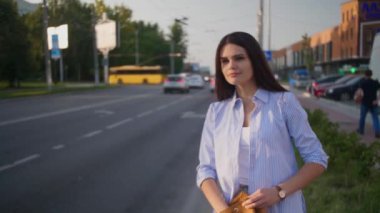 Sırt çantasından telefonu çıkaran ve şehirde taksiye binen genç bir kadın.