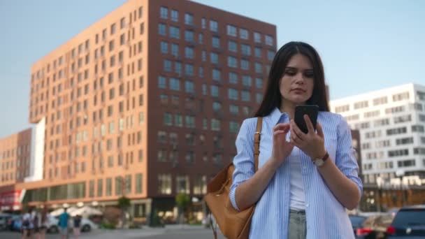 都市で携帯電話を使用しながらタクシーをキャッチする若い女性 — ストック動画