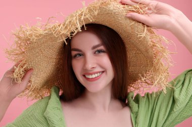 Pembe arka planda hasır şapkalı çilli güzel bir kadının portresi.