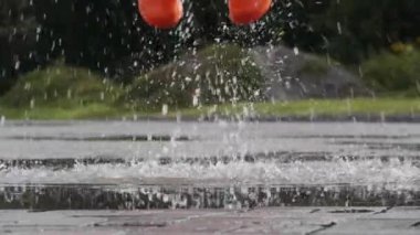 Parlak turuncu çizmeli kadın açık havada gölete atlıyor, yakın plan.