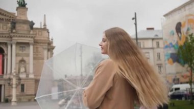 Şehirde şemsiyesi olan mutlu bir kadın.