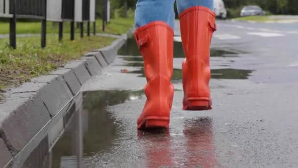 明るいオレンジ色の雨のブーツが屋外で走っている女性 バッククローズアップビュー 彼女の後に続くカメラ — ストック動画