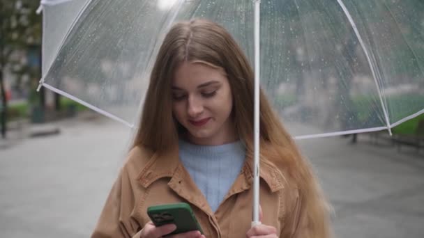Junge Schöne Frau Mit Regenschirm Mit Handy Während Jemand Freien — Stockvideo
