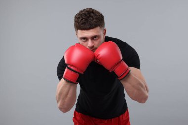 Gri arka planda boks eldivenli adam.