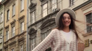 Şehir sokaklarında şık ceketli ve şapkalı mutlu genç bir kadın