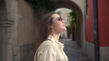 Güneş gözlüklü genç bir kadın şehirde dönüyor.