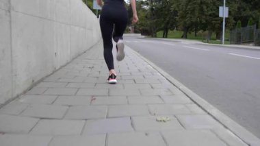 Genç sporcu kadın dışarı koşuyor, kamera arkasından gidiyor.