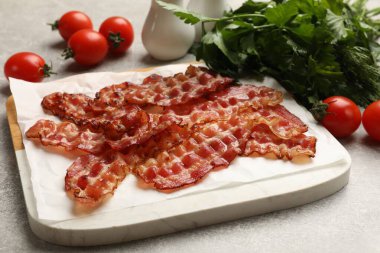 Kızarmış domuz pastırması, domates ve maydanoz. Gri desenli masa, yakın plan.