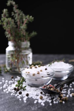 Taze kekikli tuz ve koyu gri desenli masada biber. Yakın plan.