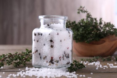 Cam kavanozda biberli tuz ve ahşap masada kekik.