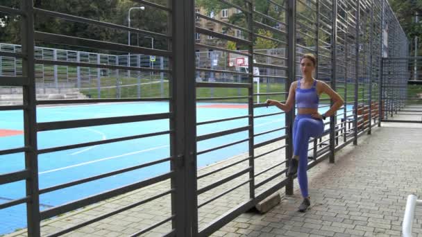 遊び場の近くで実行する前に運動をしている若いスポーティな女性 — ストック動画