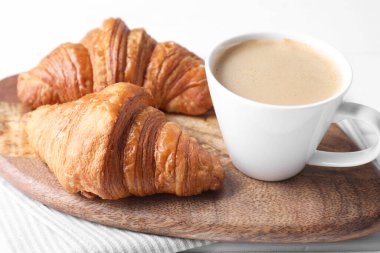 Lezzetli bir kahvaltı. Masada bir fincan kahve ve kruvasan, yakın plan.