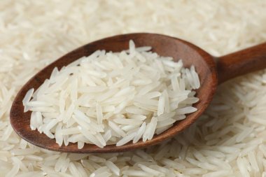 Arka plan olarak çiğ basmati pilavı ve kaşık, yakın plan.