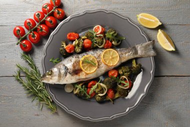 Pişmiş balık, sebzeli, biberiyeli ve limonlu gri ahşap masa, düz uzanmış