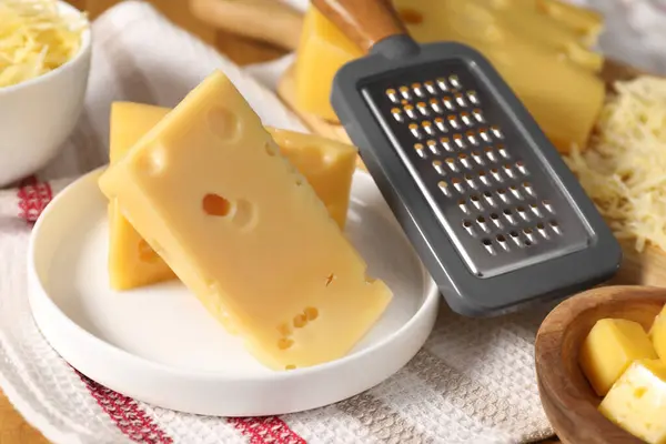 Grated, cut cheese and grater on table, closeup