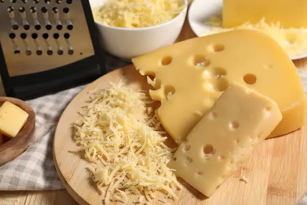Grated, cut cheese and grater on table, closeup