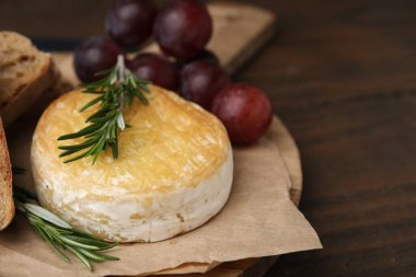 Lezzetli fırında camembert, üzümler ve biberiye ahşap masada, yakın plan. Metin için boşluk