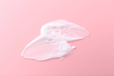 Pembe arka planda vücut bakım kremi örneği, üst görünüm.