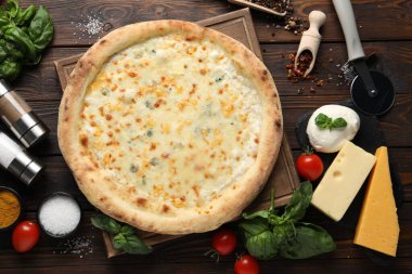 Düz kompozisyon, lezzetli peynirli pizza ve ahşap masa malzemeleri.
