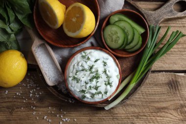 Lezzetli yoğurt, yeşil soğan, salatalık, fesleğen ve limon ahşap masada.