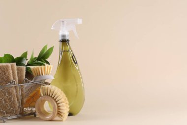 Bej arka planda bir şişe temizlik ürünü, sünger, fırça ve çiçek dekoru. Metin için boşluk