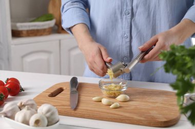 Mutfaktaki beyaz masada basın mensuplarıyla sarımsak sıkan kadın, yakın plan.