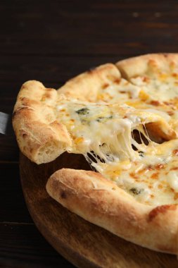 Ahşap masada leziz bir dilim peynirli pizza, yakın plan.