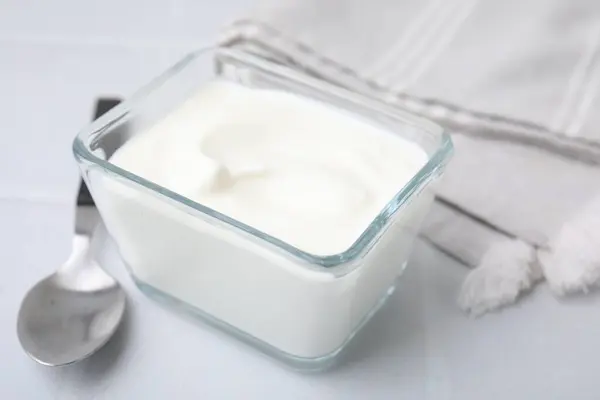 Delizioso Yogurt Naturale Ciotola Vetro Cucchiaio Tavolo Bianco Primo Piano — Foto Stock