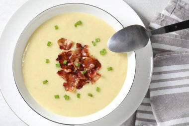 Lezzetli patates çorbası, pastırmalı ve kaşıklı beyaz masa, düz uzanmış.