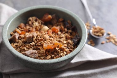 Lezzetli granola kasede ve peçete gri masada, yakın plan.