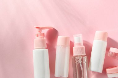 Pembe arka planda kozmetik seyahat seti, üst manzara. Metin için boşluk