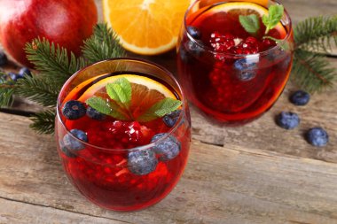 Aromatik Noel Sangria kadehleri, köknar dalları ve ahşap masa malzemeleri.