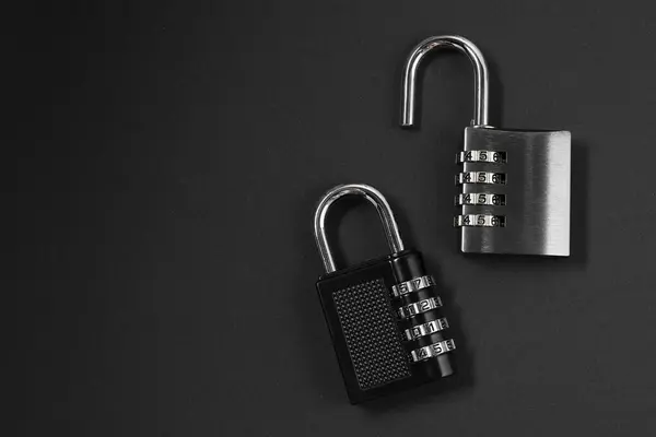 Steel combination padlocks on black background, top view. Space for text