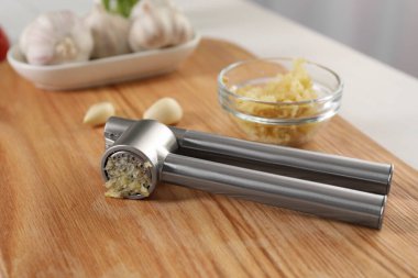 Sarımsak ezici ve kıyma, ahşap masa, yakın plan.