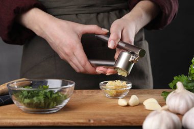 Tahta masada basınla sarımsak sıkan kadın, yakın plan.