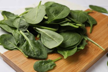 Beyaz masa üzerinde taze ıspanak yaprakları olan tahta, yakın plan.