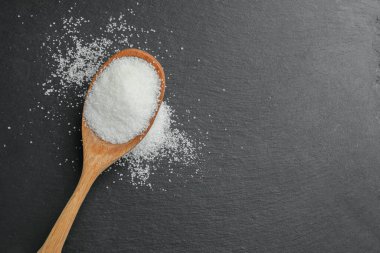 Siyah masa üzerinde granüllü şeker ile kaşık, üst manzara. Metin için boşluk