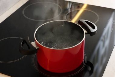 Yemek pişiriyorum. Mutfaktaki tencerenin üstünde kaynar su var.