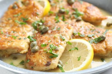 Lezzetli tavuklu piccata, tavada otlar ve limonlar, yakın plan.